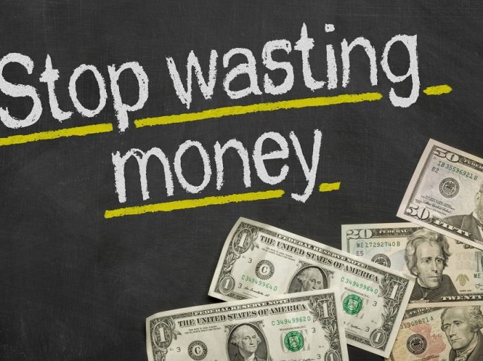 Text on blackboard with money - Stop wasting money