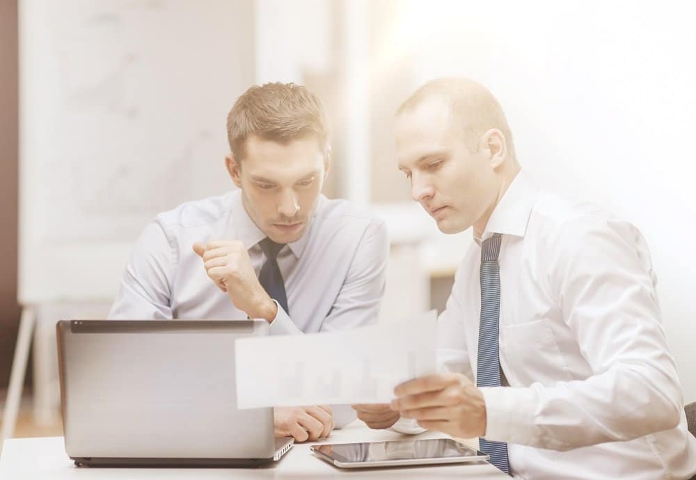 Two businessmen looking at a piece of paper talking about cybersecurity