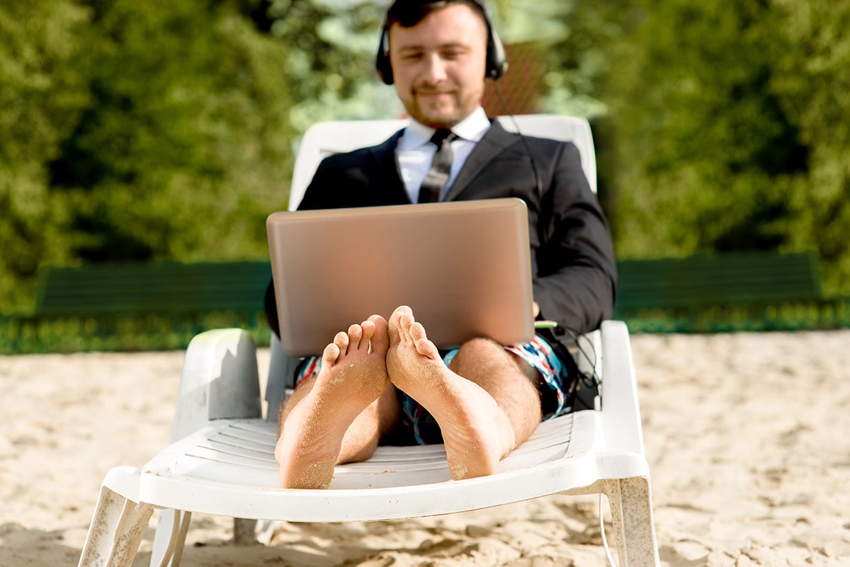 man using laptop on beach